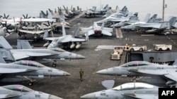 A U.S. Navy officer walks past fighter jets parked on the flight deck of the Nimitz-class aircraft carrier USS Abraham during a media tour in Port Klang, on the outskirts of Kuala Lumpur, Malaysia, Nov. 26, 2024.