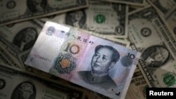 Foto ilustrasi yang menunjukkan mata uang China, Yuan, di atas kumpulan uang kerta dolar AS. (Foto: Reuters/Dado Ruvic)