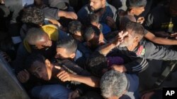 Warga Palestina berdesak-desakan di depan sebuah toko roti di Deir al-Balah, Jalur Gaza, untuk mendapatkan roti pada 21 November 2024. (Foto: AP/Abdel Kareem Hana)