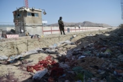 A Taliban fighter stands guard at the site of the Aug. 26 suicide bombing, which killed scores of people including 13 US troops, at Kabul airport on Aug. 27, 2021.