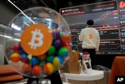 Seorang karyawan mengamati papan tanda elektronik yang menampilkan harga bitcoin dan mata uang kripto lainnya di ruang tunggu bursa mata uang kripto Bithumb di Seoul, Korea Selatan, 21 November 2024. (Foto: Ahn Young-joon/AP Photo)