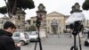 FILE - A reporter waits outside the Lazzaro Spallanzani National Institute for Infectious Diseases in Rome, Jan. 31, 2020, where two Chinese tourists who had tested positive for the coronavirus were being held in isolation.