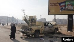 Seorang perempuan melewati kendaraan rusak setelah pemberontak HTS berusaha maju ke Homs, Hama, Suriah, 6 Desember 2024. (Foto: Mahmoud Hasano/Reuters)