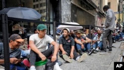 Sejumlah migran tampak mengantre di luar The Roosevelt Hotel yang digunakan oleh pemerintah kota New York untuk menampung sementara para migran, pada 31 Juli 2023. (Foto: Ap/John Minchillo)