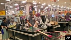 Sejumlah kasir di sebuah supermarket di mal AEON, Tangerang, melayani pembeli dibalik pembatas lapisan plastik untuk mencegah penularan virus corona, 22 Mei 2020. (Foto: AP)