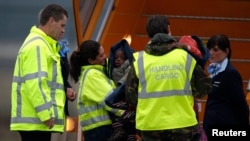FILE - Flight attendants and a woman believed to be from a Dutch adoption association escort some of the 106 children from a Dutch relief flight arriving in the Netherlands from Port-au-Prince, in Eindhoven, Jan. 21, 2010.