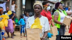 Seorang perempuan menerima bantuan makanan dari relawan saat lockdown atau karantina wilayah untuk mencegah penularan virus corona (COVID-19), di Lagos, Nigeria, 9 April 2020.