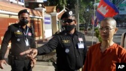 FILE - Court securities direct Cambodian-American lawyer Theary Seng, right, dressed in a prison-style orange outfit, to the entrance of Phnom Penh Municipal Court in Phnom Penh, Cambodia, Tuesday, Jan. 4, 2022. 