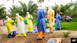 Des agents de la santé, vêtus d’équipement de protection contre le virus Ebola, transportent sur une civière les restes d'un enfant nouveau-né suspecté mort après avoir contracté l’épidémie, à Dubreka, Guinée, le 19 juin 2015