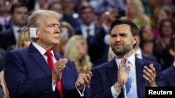 Republican presidential nominee and former U.S. President Donald Trump applauds with Republican vice presidential nominee J.D. Vance during Day 1 of the Republican National Convention at the Fiserv Forum in Milwaukee, Wisconsin, July 15, 2024. 