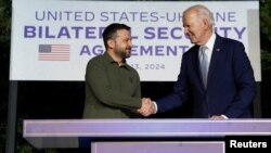 Presiden AS Joe Biden dan Presiden Ukraina Volodymyr Zelenskiy berjabat tangan usai menandatangani perjanjian bilateral keamanan baru di Fasano, Italia, Kamis, 13 Juni 2024. (Foto: Kevin Lamarque/Reuters)