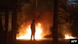 Dečak posmatra dok se plamen i dim dižu iza njega na mestu nasilja Njutanabiju, severno od Belfastga, u Severnoj Irskoj, 3. aprila 2021.