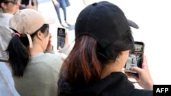 Mladi u Melburnu gledaju u svoje telefone, 28. novembra 2024. (Foto: William West/AFP)