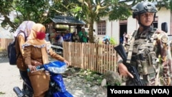 Dua perempuan melintas di depan aparat keamanan di Poso. (Foto ilustrasi: Yoanes Litha). Kaum perempuan rentan menjadi korban langsung serangan teroris karena berada di lokasi ketika serangan terjadi.