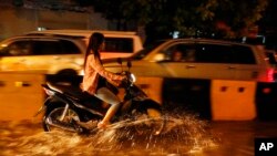 រូបឯកសារ៖ អ្នក​ធ្វើ​ដំណើរ​តាម​ម៉ូតូ​ម្នាក់​បើ​កាត់​ផ្លូវ​លិច​ទឹក​ដោយសារ​តែ​ភ្លៀង​ធ្លាក់​មួយ​មេឃ​ធំនៅ​ទីក្រុង​ភ្នំពេញ កាល​ពី​ថ្ងៃ​សុក្រ ទី៣១ ខែ​កក្កដា ឆ្នាំ២០១៥។ (AP/Heng Sinith) 