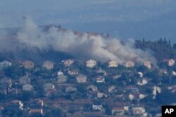 Asap mengepul dari sela-sela rumah di Kota Metula di perbatasan Israel utara yang terkena tembakan Hizbullah, terlihat dari sisi Kota Marjayoun, Lebanon, Lebanon, Sabtu, 22 Juni 2024. (Foto: AP)