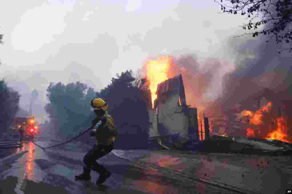 A firefighter battles the advancing Palisades Fire as it burns a structure in the Pacific Palisades neighborhood of Los Angeles, Jan. 7, 2025.&nbsp;