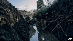 Sejumlah tentara Ukraina bersembunyi di dalam parit untuk menghindar dari serangan Rusia di garis depan pertempuran di dekat Bakhmut, Donestk, Ukraina, pada 5 Maret 2023. (Foto: AP/Libkos)