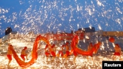 2013年2月10日在北京的一处游乐园庆祝农历新年的火龙舞表演中，火龙队员在铁水花与干花的施放中舞着火龙