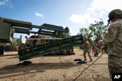 Members of the U.S. Army prepare a crane for loading the Army Tactical Missile System on to the High Mobility Artillery Rocket System in Queensland, Australia, on July 26, 2023. (U.S. Army via AP)