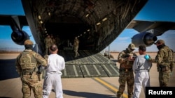 The first U.S. military aircraft to carry detained migrants to Guantanamo Bay is boarded from an unspecified location in the U.S.