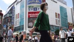 Para pejalan kaki melintasi persimpangan jalan di dekat Stasiun Shimbashi di Tokyo, Kamis, 29 Juli 2021, sehari setelah diumumkannya kasus virus corona tertinggi di kota tuan rumah Olimpiade ini. (Foto AP/Kntaro Komiya)