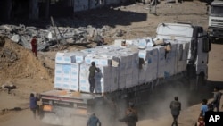 Palestinians chase humanitarian aid trucks that arrived through the Kerem Shalom crossing from Egypt into the Gaza Strip, in Rafah, Jan. 21, 2025.