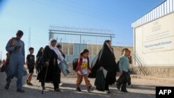 Para pengungsi Afghanistan berjalan setelah dideportasi dari Iran, di sebuah pusat pendaftaran di dekat perbatasan Afghanistan-Iran di distrik Islam Qala, provinsi Herat, 12 September 2024. (Mohsen KARIMI / AFP)