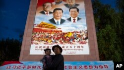 资料照：在西藏拉萨布达拉宫外，一名男子抱着一个小女孩在一幅宣传中国历届领导人的画像前拍照。(2021年6月1日)