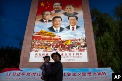 FILE - A man holds a girl as they pose for a photo in front of a large mural depicting Chinese President Xi Jinping, bottom center, at the base of the Potala Palace in Lhasa in western China's Tibet Autonomous Region on June 1, 2021.