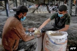 Workers portion out flour rations during the distribution of humanitarian aid in Gaza City on March 17, 2024.
