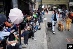 Para migran Amerika Tenga antre menunggu di luar The Roosevelt Hotel yang digunakan kota sebagai tempat tinggal sementara di kota New York.