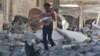 A boy carries bread as he makes his way through rubble of a site hit by an airstrike in the rebel-held area of Aleppo's al-Sukari district, Syria, May 30, 2016. 