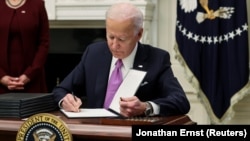 Presiden AS Joe Biden menandatangani perintah eksekutif di Gedung Putih, Kamis 21/1 (Foto: Reuters/Jonathan Ernst)