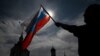 Seorang pria mengibarkan bendera nasional Rusia, 11 Juni 2023. Bos mata-mata Rusia pada Selasa (20/2) mengatakan seorang pilot yang membelot ke Ukraina dengan helikopter militer dan kemudian dilaporkan ditembak mati di Spanyol adalah “mayat moral.” (Foto: Ilustrasi/AFP)