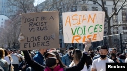 Seorang perempuan menunjukkan poster dalan pawai menentang kejahatan rasial terhadap orang Amerika keturunan Asia dan Kepulauan Pasifik di Kota New York, 21 Maret 2021. 