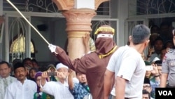 Algojo pelaksana cambuk mengayunkan rotan ke punggung pelanggar syariah di Banda Aceh, 19 September 2014 (Foto: dok).