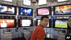 资料照：在2006年北京国际广播电影电视设备展上，一位男士站在一系列电视机前。