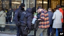 Polisi anti huru-hara memeriksa tas para penonton konser grup rock "Picnic" dan orkestra simponi "Tavrichesky" di gedung konser Oktyabrsky Concert Hall, St. Petersburg, Rusia, Rabu, 27 Maret 2024. (Foto: Dmitri Lovetsky/AP Photo)