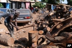 FILE - Lassana Coulibaly cuts firewood to be distributed to people in Senou, Mali, Oct. 11, 2024.