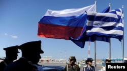 FILE - Greek police and army officers stand by Greek, Russian and EU flags as they wait for the arrival of Russian President Vladimir Putin in Athens airport, May 27, 2016. 