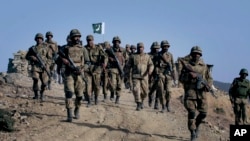 FILE - Pakistani troops walk on a hilltop post near Ladha, a town in the troubled Pakistani tribal region of Waziristan along the Afghan border.