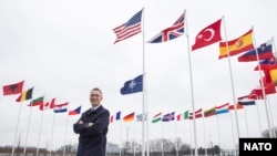 Jens Stoltenber, generalni sekretar NATO-a ispred zastave Severno-atlantskog saveza i zastava 29 clanica najvećeg odbrambenog saveza na svetu