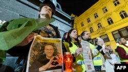 People hold portraits of the late Russian opposition leader Alexey Navalny, who died in a Russian Arctic prison, as they gather to pay tribute during a candle vigil in downtown Zagreb, Croatia, Feb. 23, 2024. Navalny's body reportedly was handed over to his mother on Feb. 24.