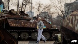 ស្ត្រី​ម្នាក់​ដើរ​កាត់​ការ​តាំង​ពិព័រណ៍​រថយន្ត​យោធា​រុស្ស៊ី​ដែល​ត្រូវ​បាន​បំផ្លាញ​នៅ​លើ​ទីលាន Mykhailivska ក្នុង​ក្រុងកៀវ កាលពី​ថ្ងៃទី១៤ ខែកុម្ភៈ ឆ្នាំ២០២៥។