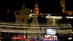 Warga Kristen Palestina menyalakan lampu-lampu pohon Natal di luar gereja Nativity, Bethlehem, Tepi Barat yang diduduki Israel (foto: dok). 
