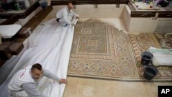 In this Dec. 6, 2018 photo, restoration experts work on a mosaic inside the Church of the Nativity, built atop the site where Christians believe Jesus Christ was born, in the West Bank City of Bethlehem.