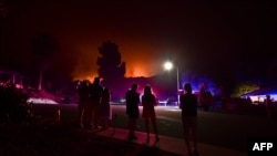 Orang-orang menyaksikan api kebakaran lahan membakar rumah-rumah di Arcadia, California, 13 September 2020.
