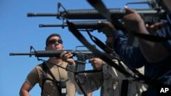 FILE - US Navy sailors shoot M-16 assault rifles aboard the USS Arleigh Burke. The global defense market rose by $6.6 billion in 2015, up to a total of $65 billion.