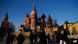 FILE - People walk on the Red Square next to St. Basil's Cathedral and the Spasskaya tower of the Kremlin on a sunny day in Moscow, Nov. 26, 2024. 